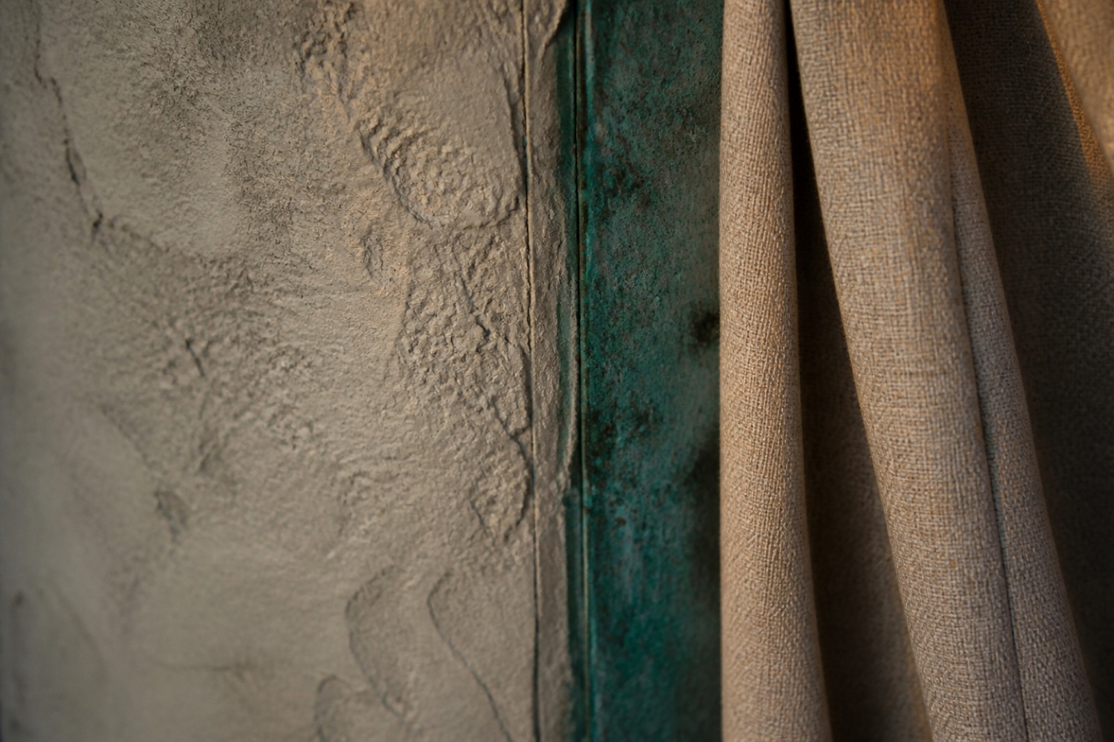 Close-up of plaster meeting linen and oxidized copper